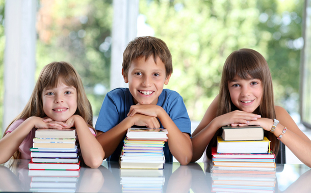 Happy schoolchildren with many books.